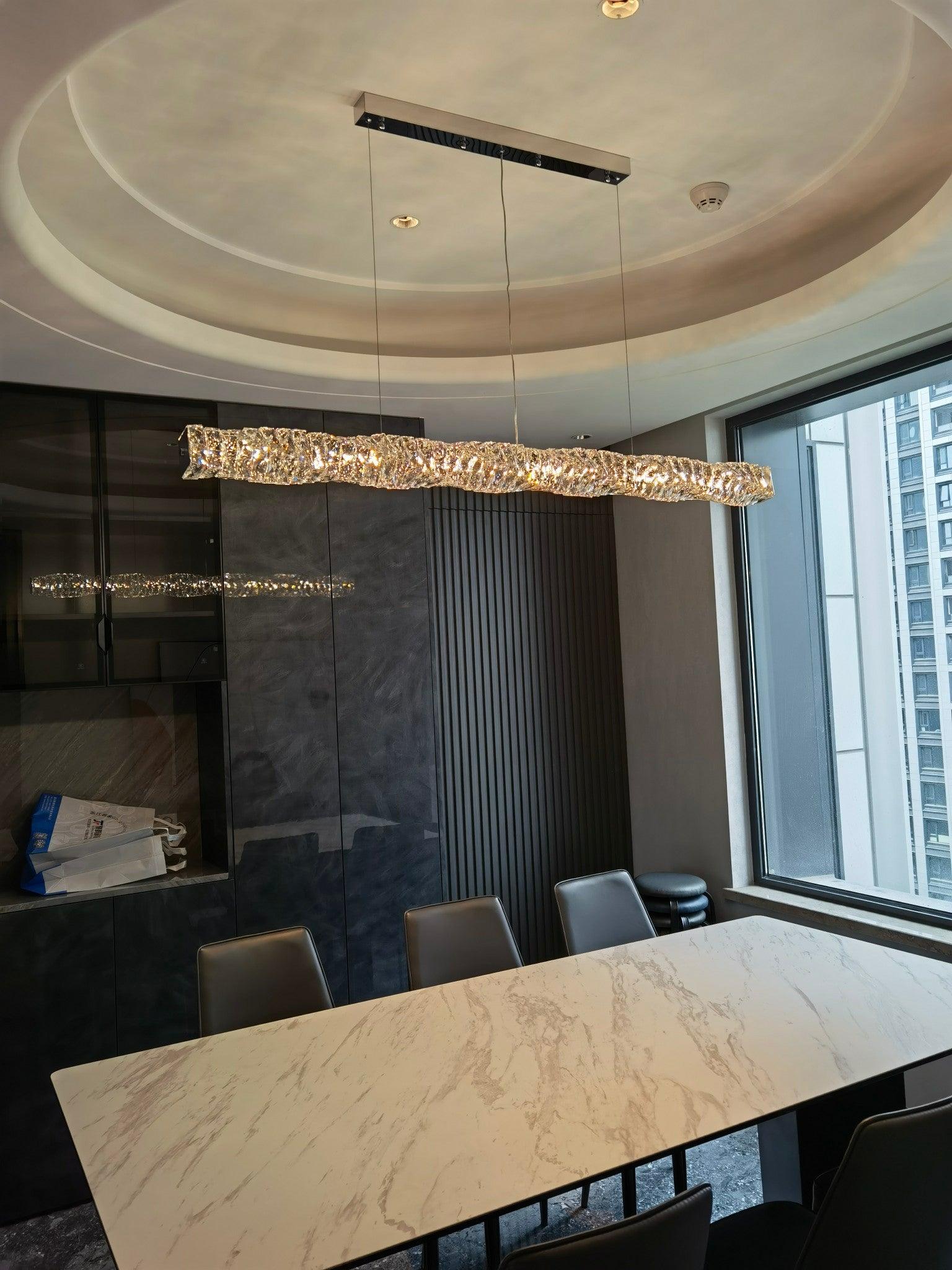 Long crystal pendant above a marble dining table beneath a circular recessed ceiling