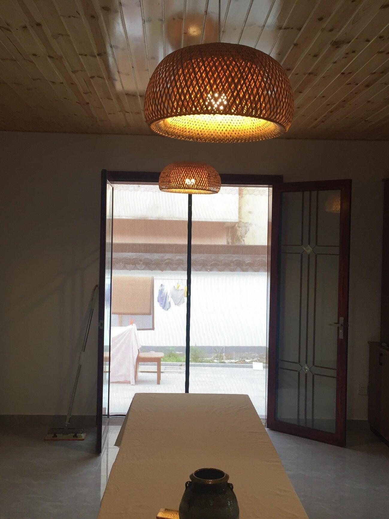 Woven bamboo pendant glowing above long table