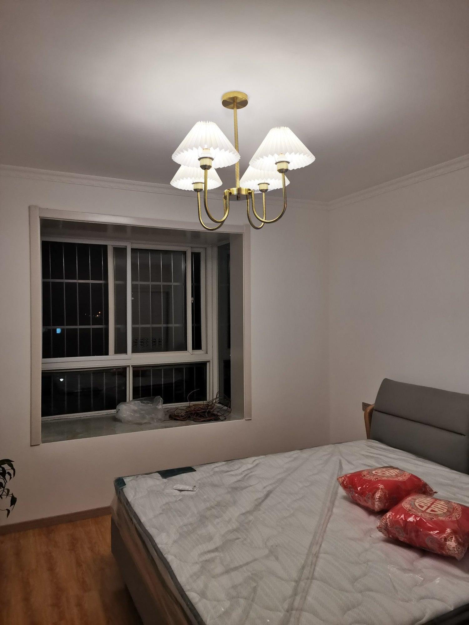 Lit Lenore chandelier above a bed near a barred window