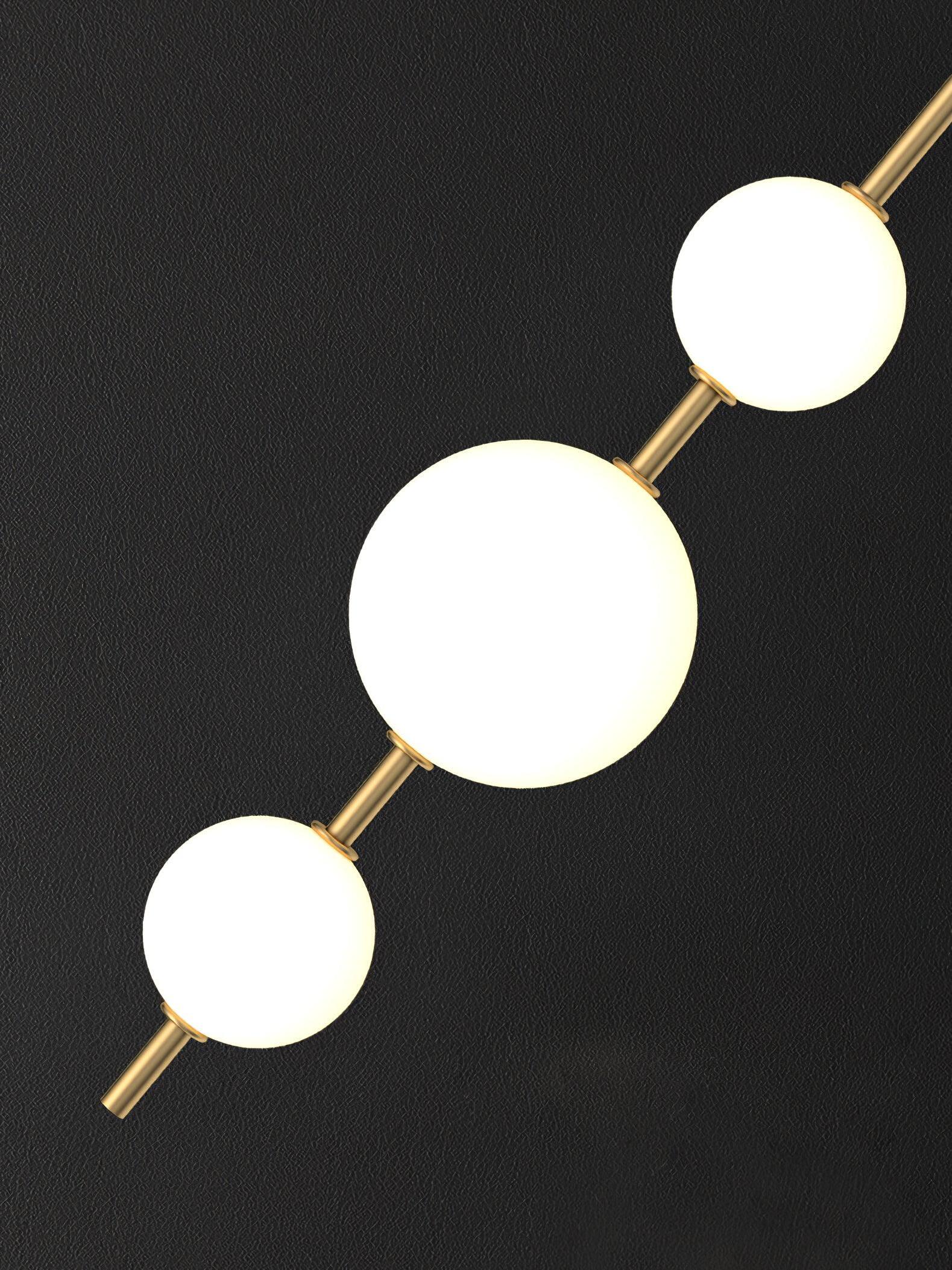 Diagonal close-up of three glowing white globes linked by brass-tone stems on a dark textured background