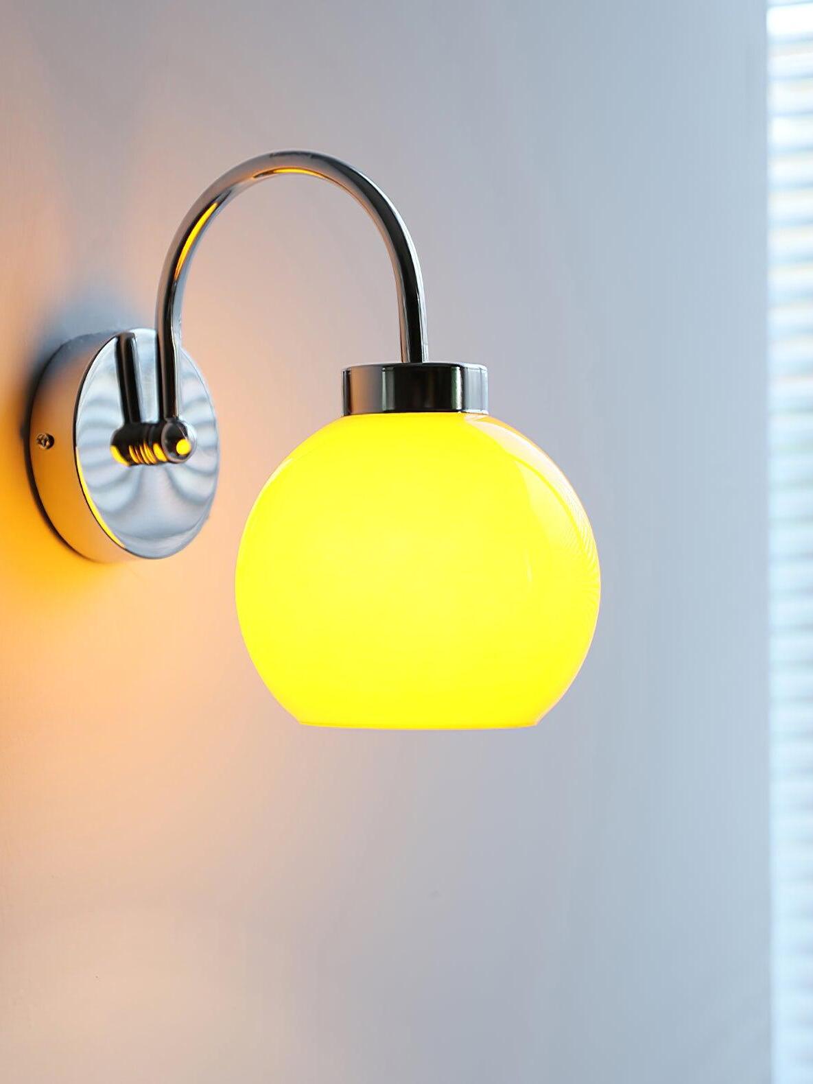 Close lit yellow-glowing globe below silver-tone arch against softly lit wall