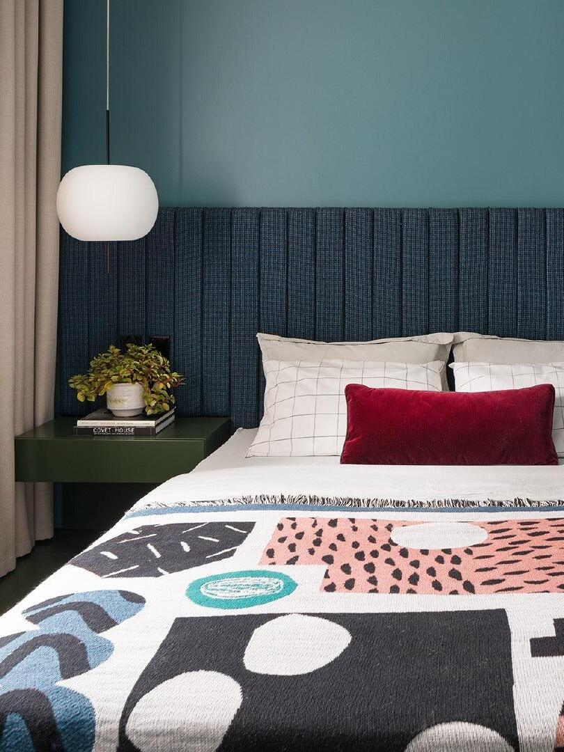 White pendant with a black stem beside a bed