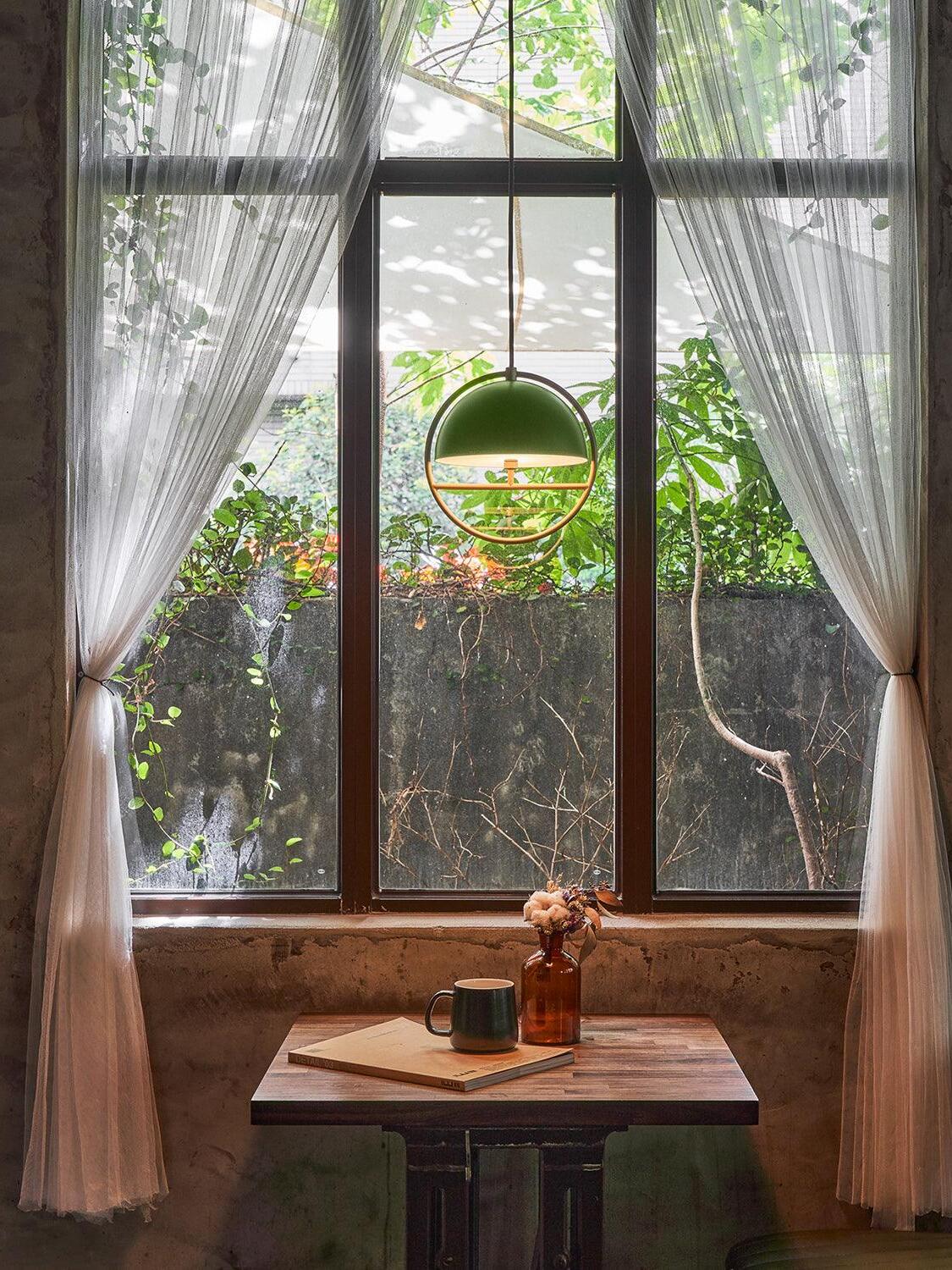 Green ring pendant beside curtained window