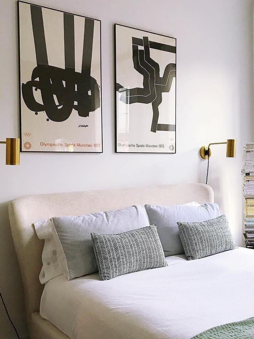 Bedroom with two brass-tone wall lights beneath framed artwork