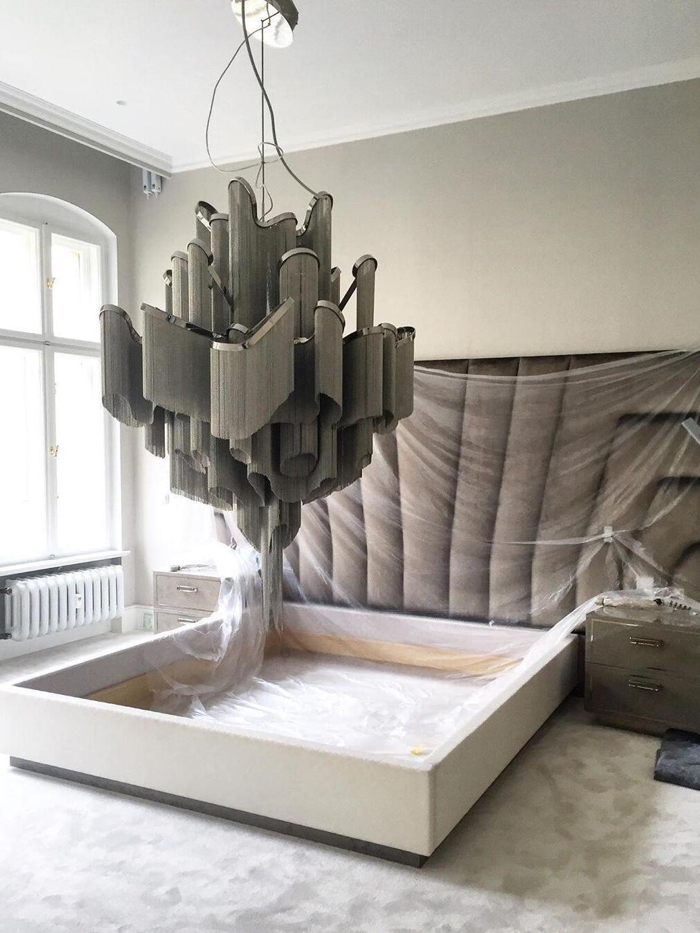 Tiered dark-looking chandelier over a bed