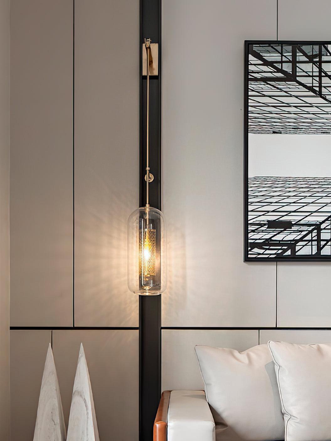Glowing glass capsule fixture beside a paneled bedroom wall, framed artwork and pillows
