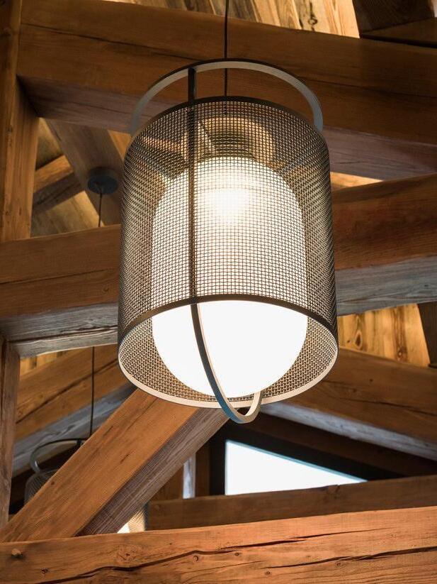 Black mesh pendant and pale inner diffuser below timber ceiling