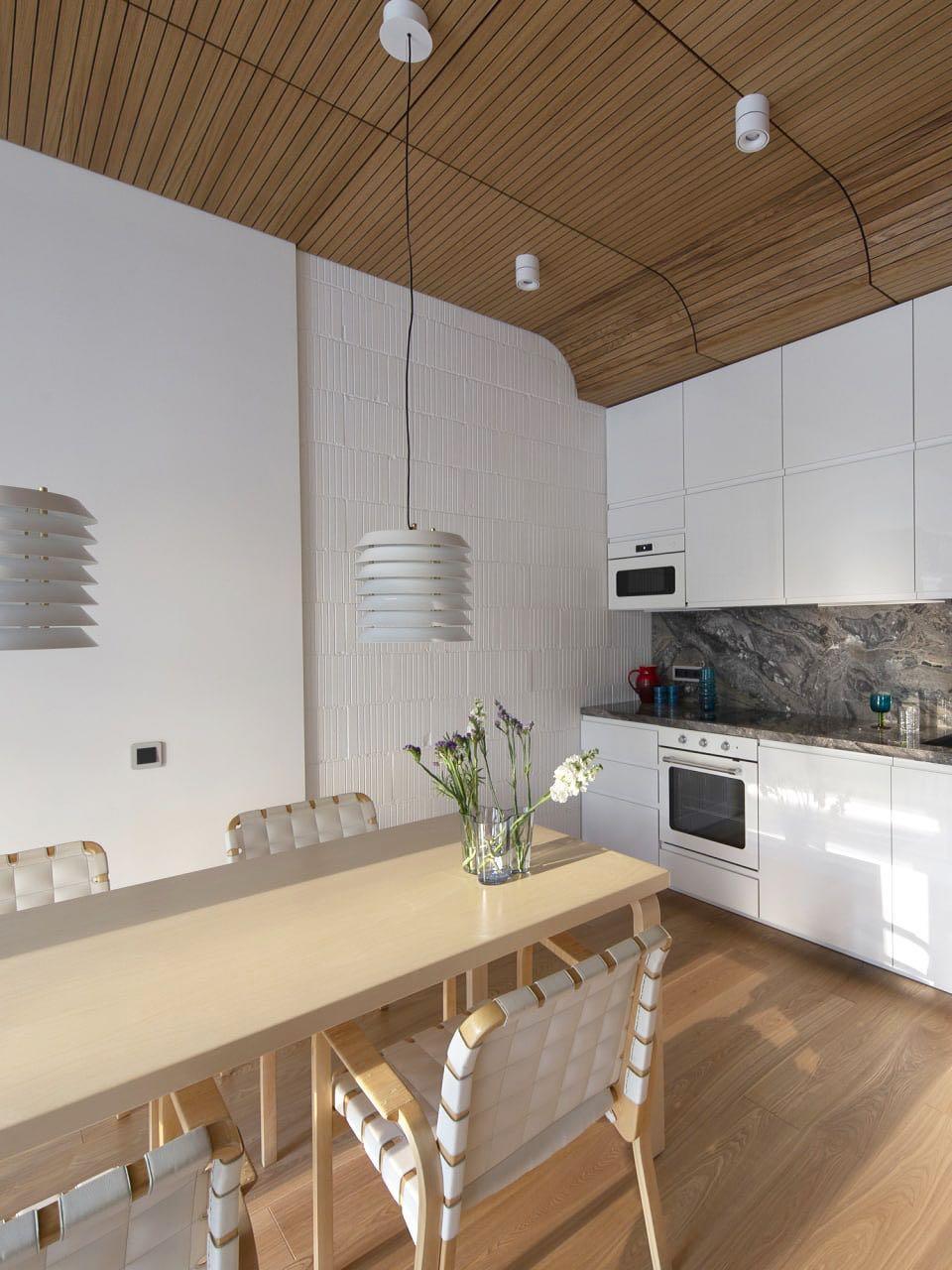 Multiple white layered pendants above a long wood kitchen table