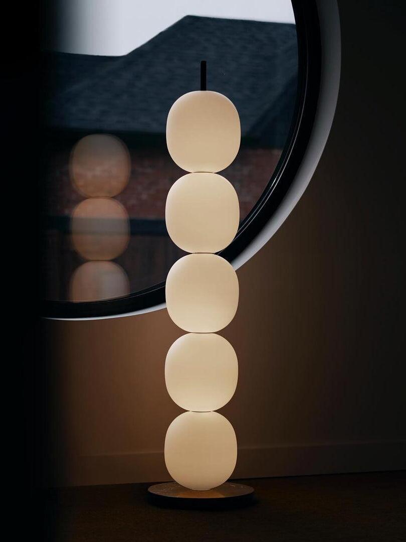 Glowing stacked-globe lamp beside circular mirror
