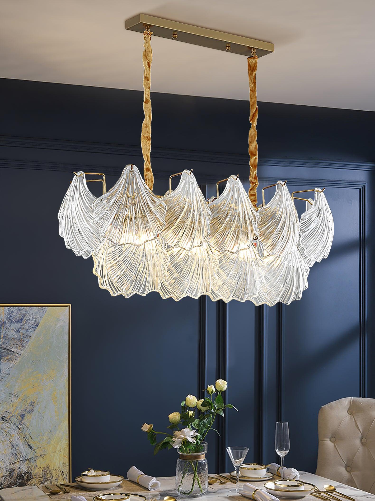 Oblong ribbed glass light suspended from a rectangular canopy above a table with flowers and glasses in a dark blue room