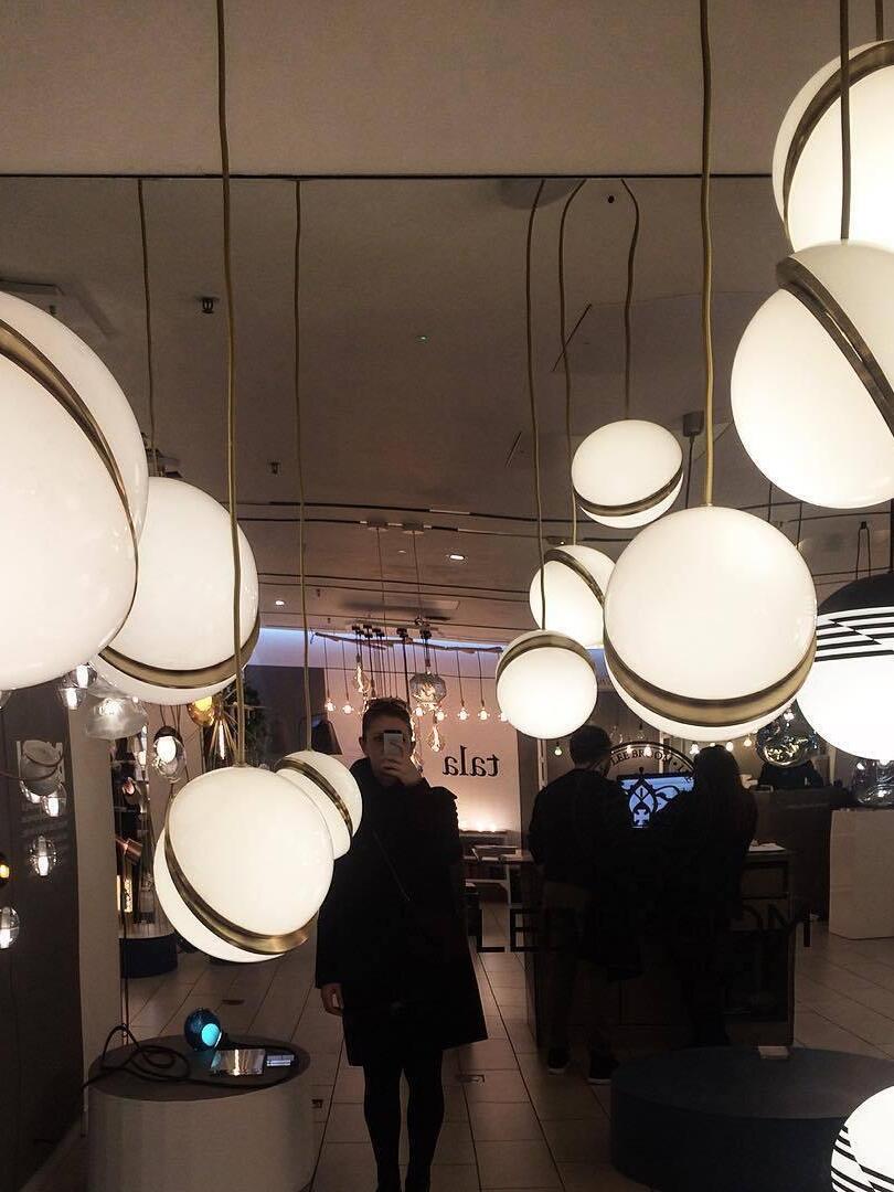 Crescent globe pendants, other fixtures and reflections in a mirrored showroom with people