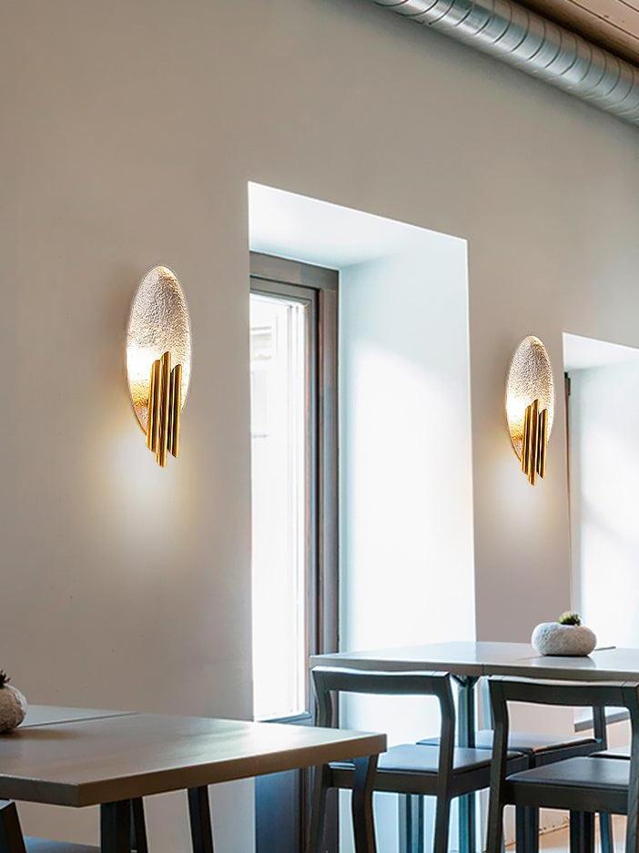 Two silver-tone oval sconces beside tall windows above tables