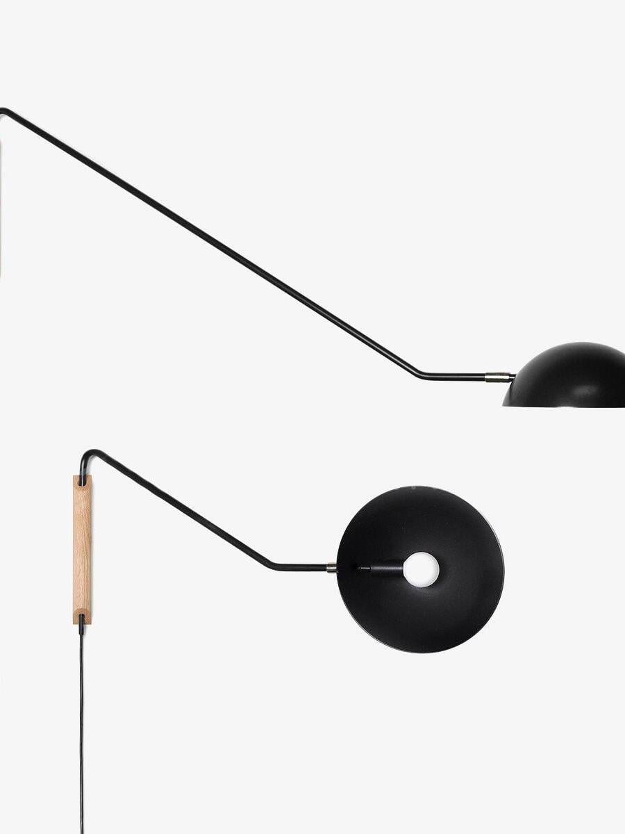 Two views of a black dome wall lamp with long arm, light wooden mounting block, round bulb and hanging cord on white