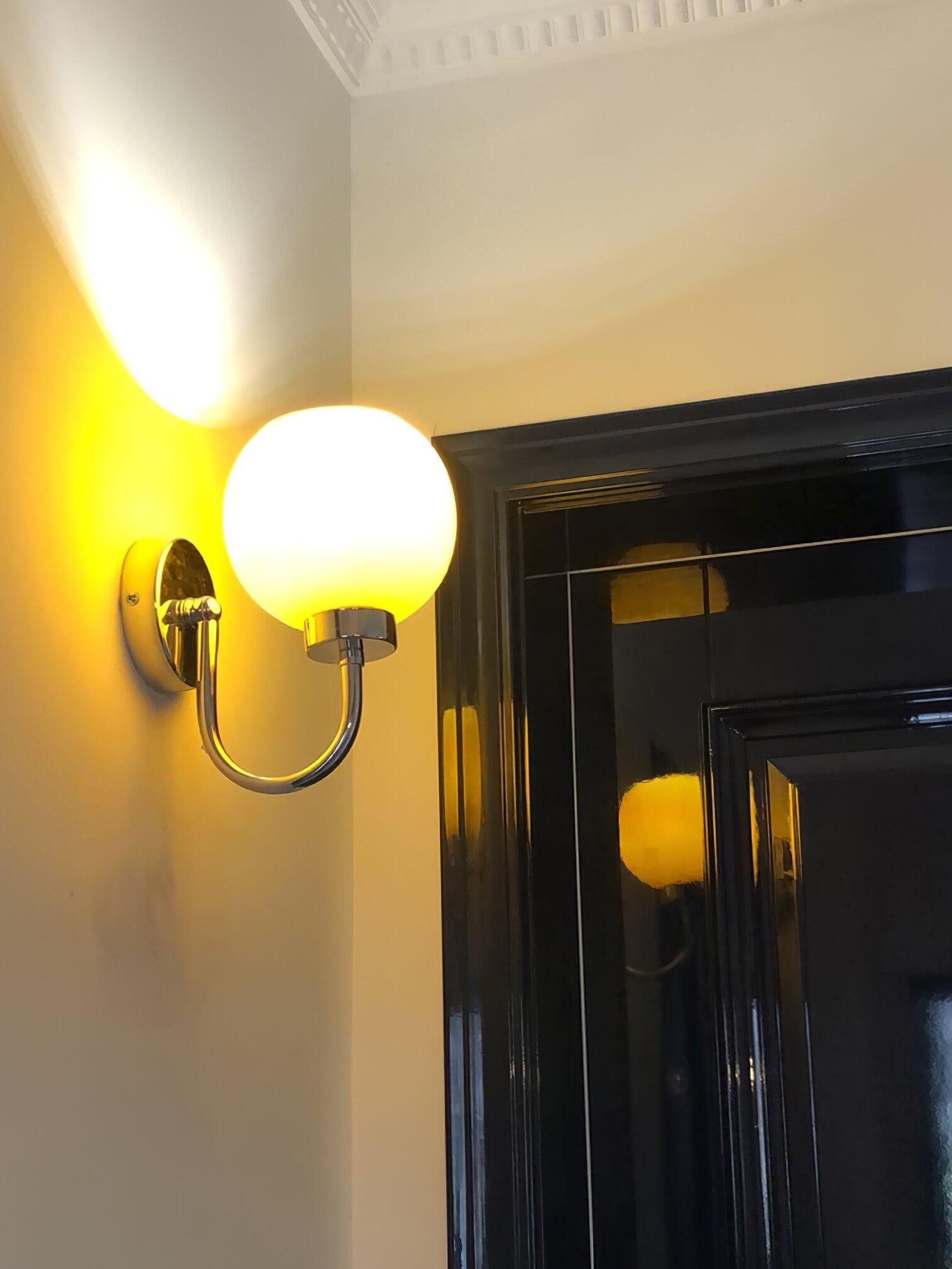 Lit pale globe above curved arm beside dark framed glazing