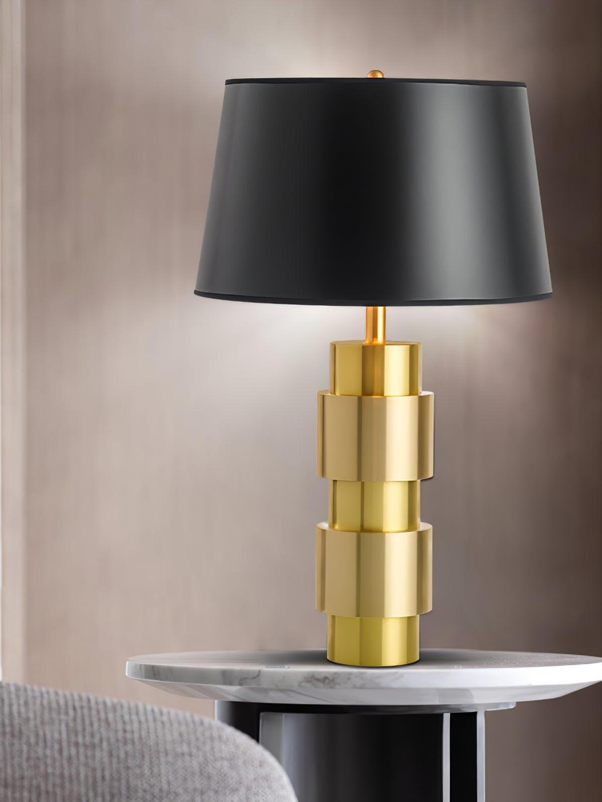 Black-shade Jean table lamp on a round pale tabletop against a softly lit wall