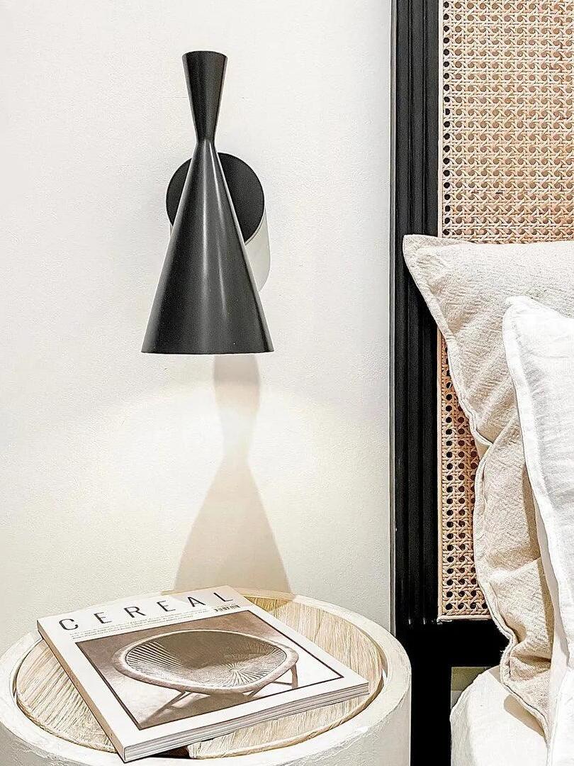 Close black Beat wall light beside a bed and rattan headboard