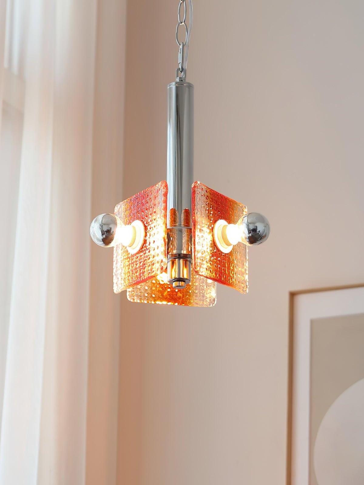 Illuminated Alohi orange glass pendant beside a pale curtain
