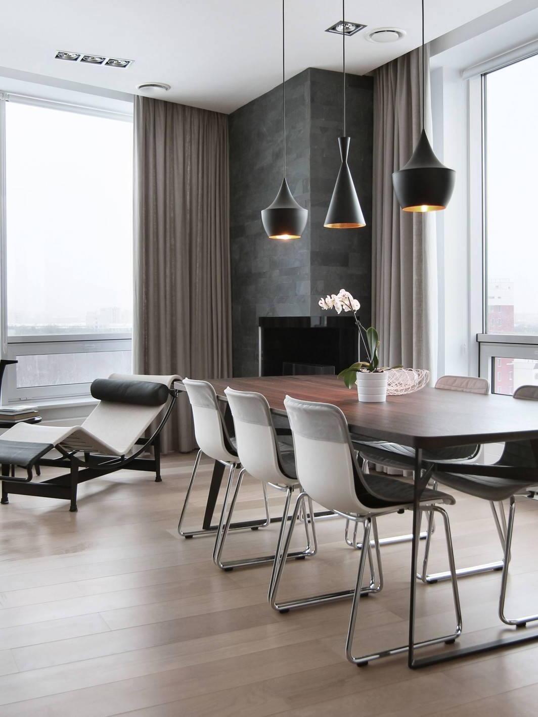 Black pendants above a dining table beside curtains