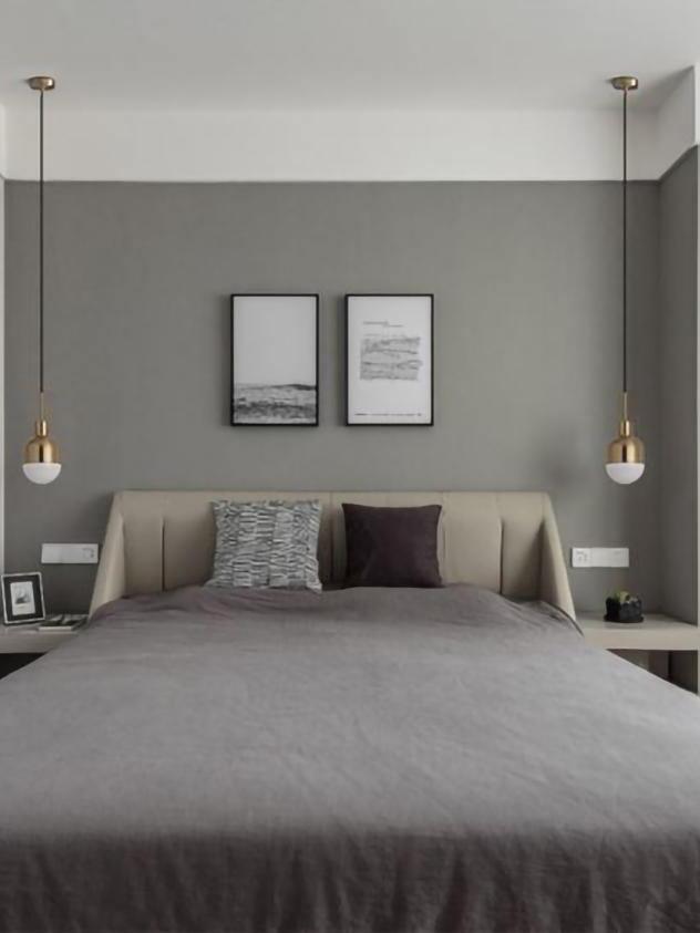 Two Niku pendants beside a cream headboard and gray bed, with framed prints on the wall