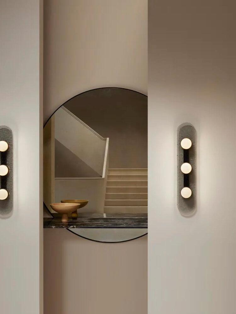 Modulo wall lights flanking a round mirror that reflects a staircase