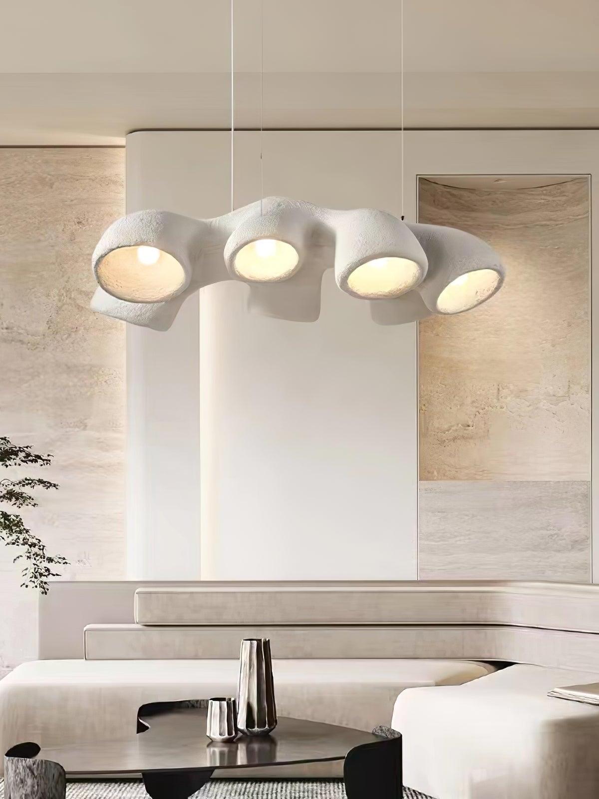 Glowing white undulating pendant above curved pale seating and a dark table with textured wall art behind