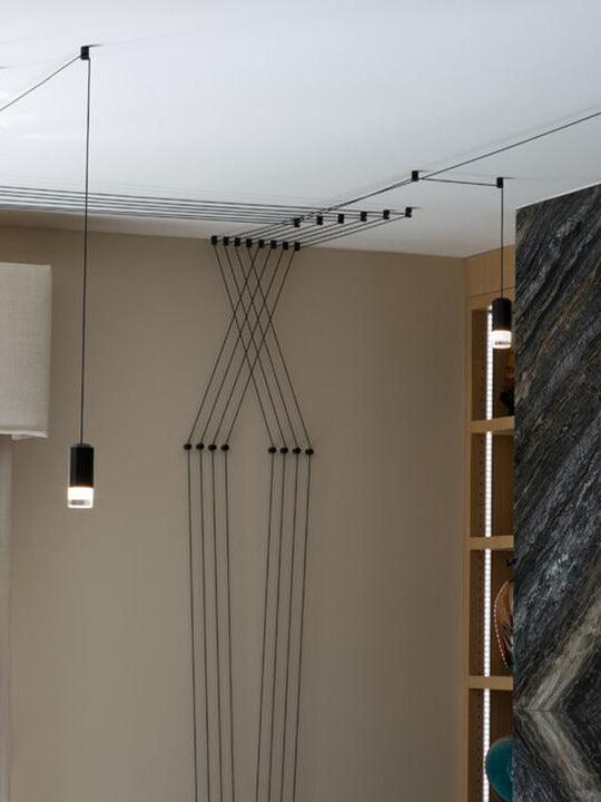 Black cables crossing down a wall and across a ceiling beside a pendant head