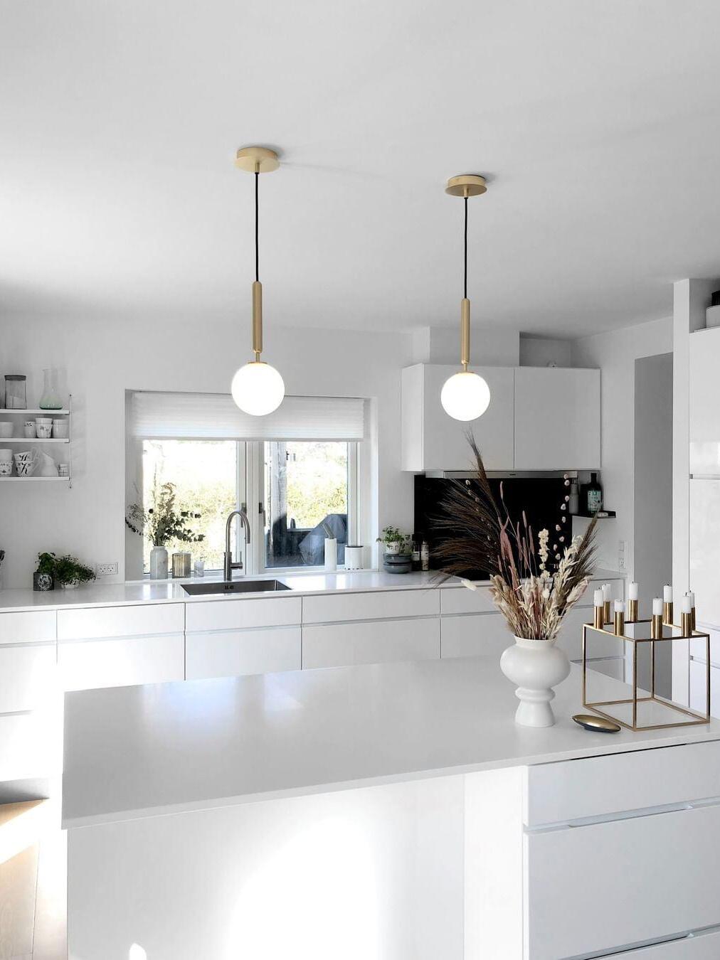 Gold-stem white-globe pendants in a bright kitchen