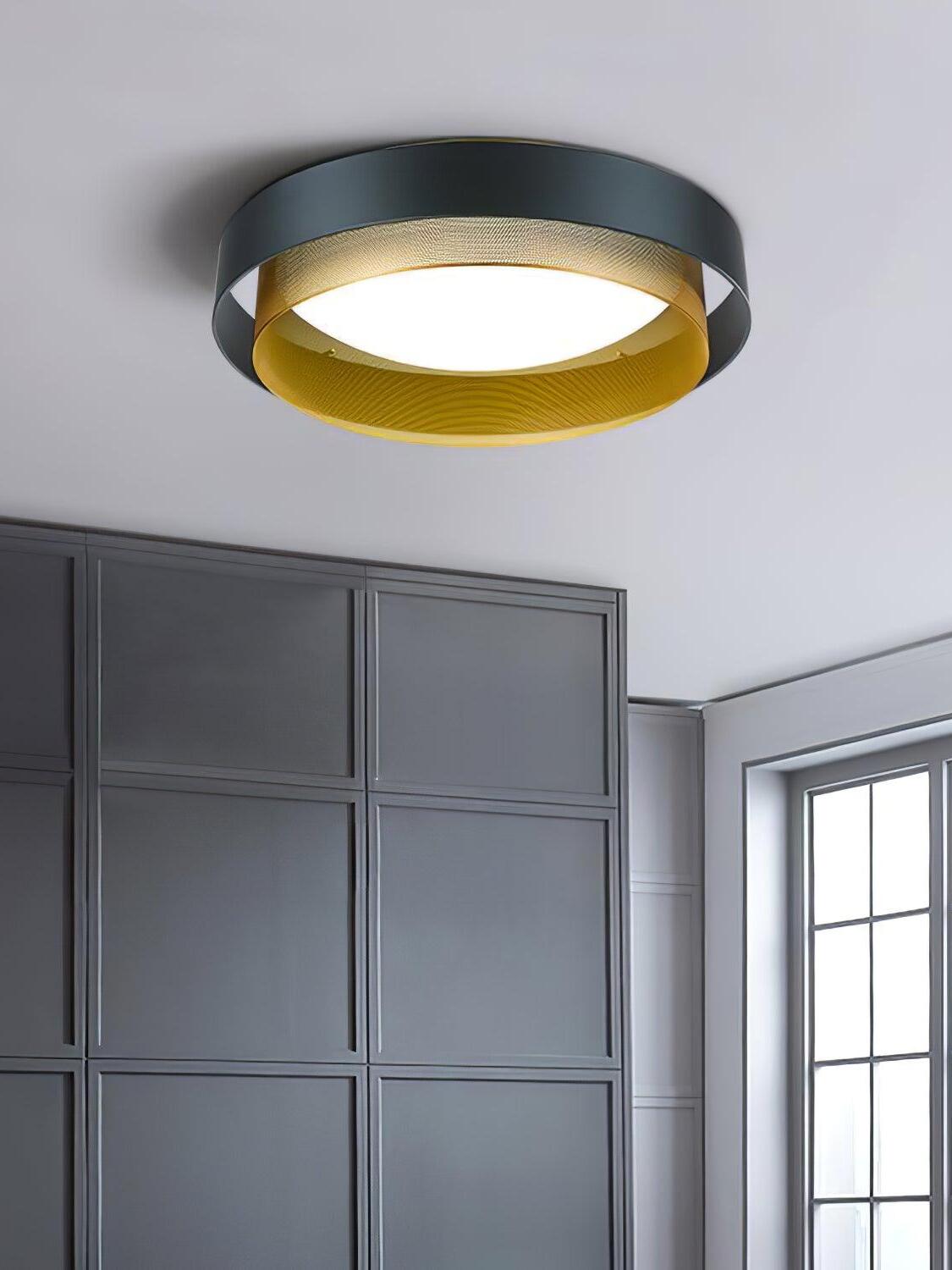 Illuminated black and gold Nolan ceiling light beside a dark panelled wall and window