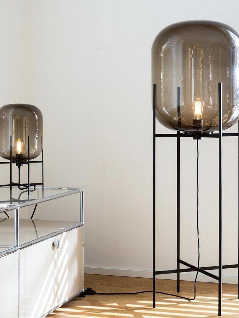 Tall and short glass lamps beside a low mirrored cabinet.