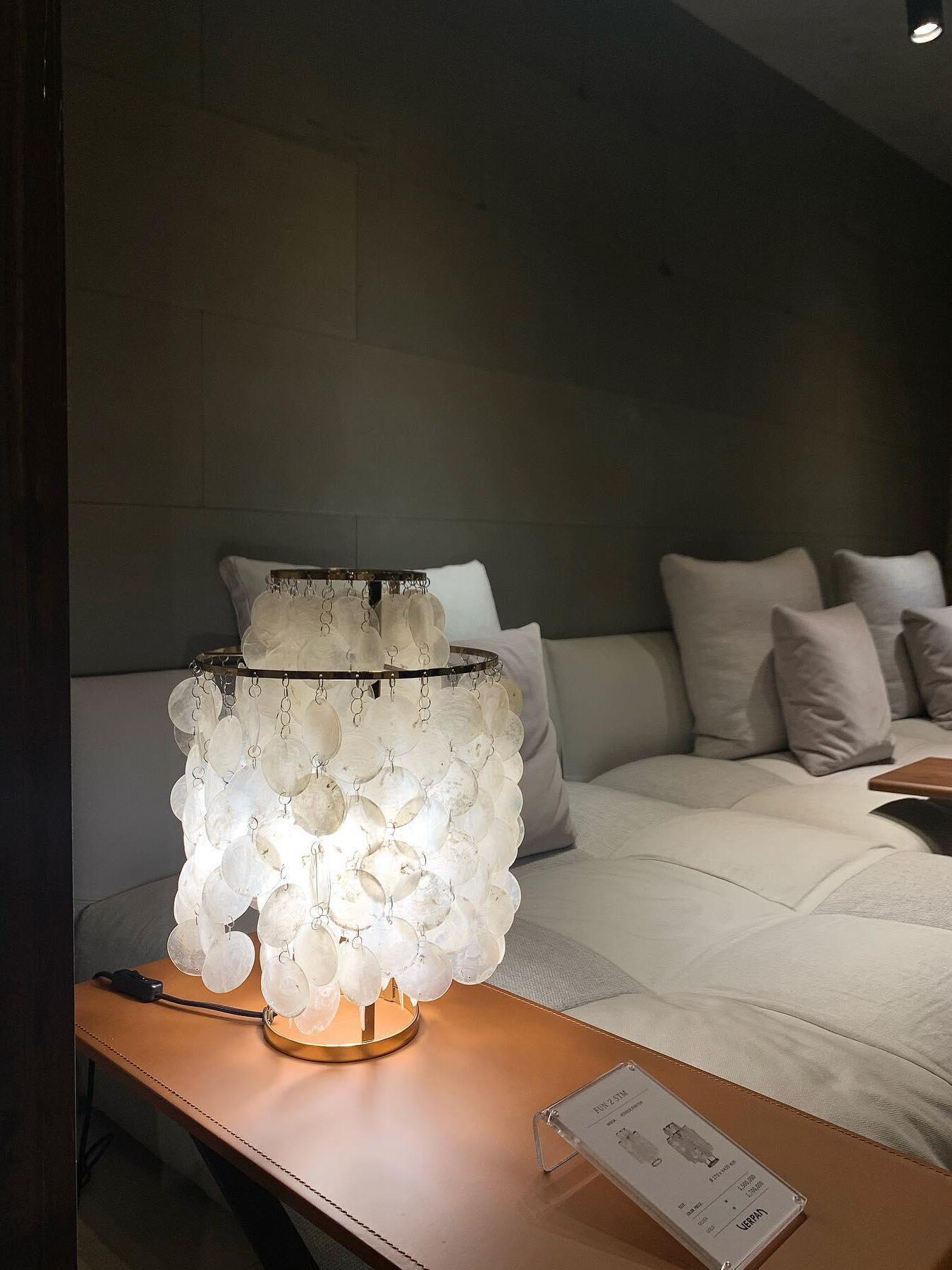 Lit shell table lamp on wooden bedside surface