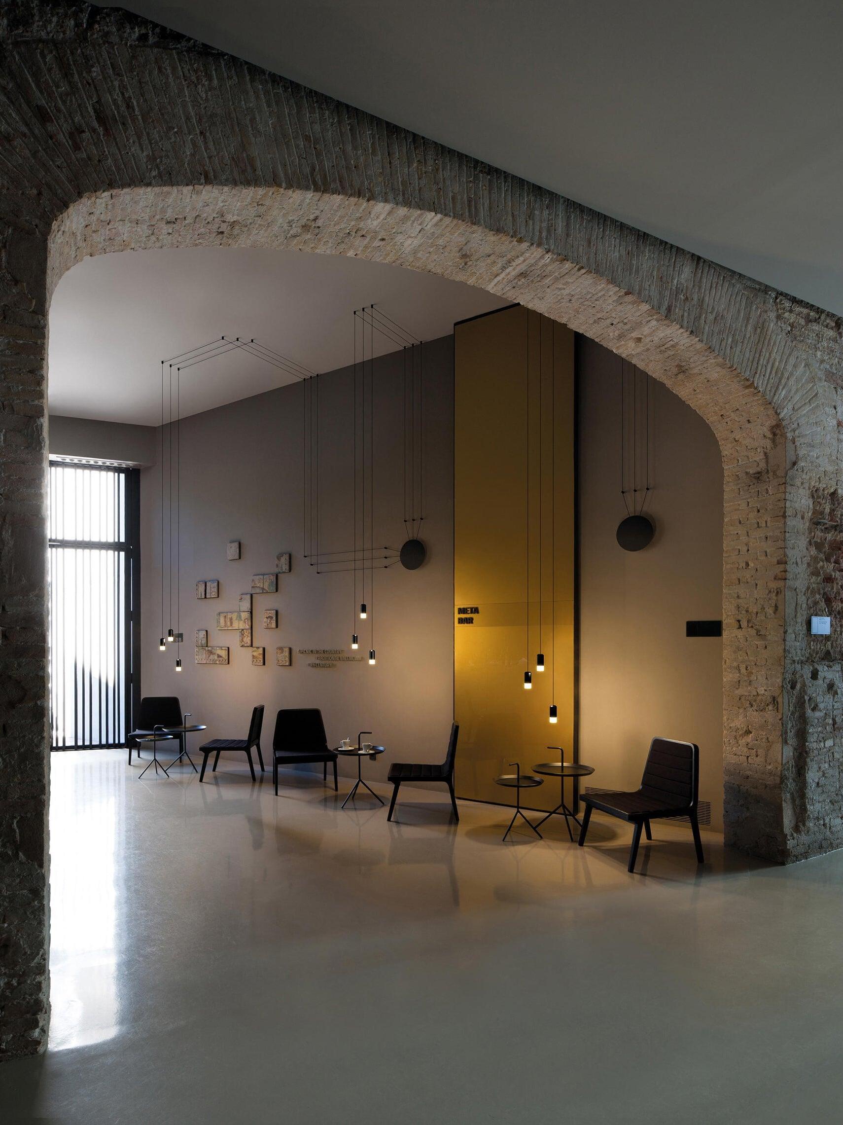 Single-head wall cable arrangements behind small tables under a stone arch