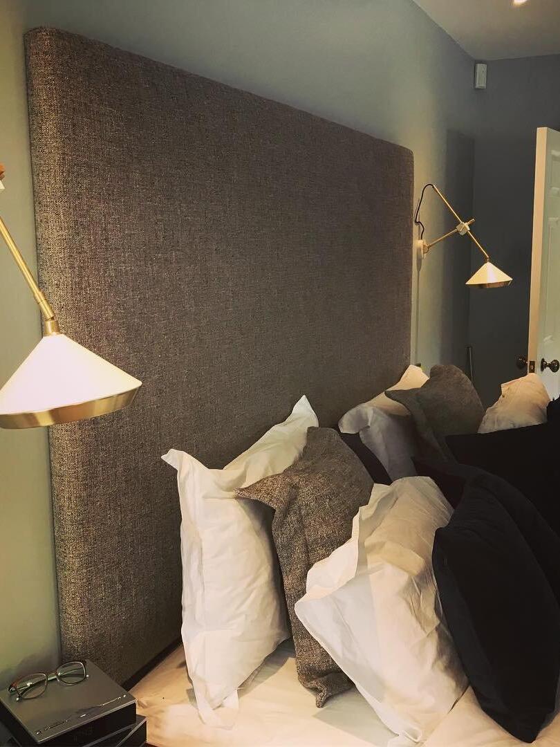 White cone wall lights beside a tall brown headboard, with one shade close to the foreground