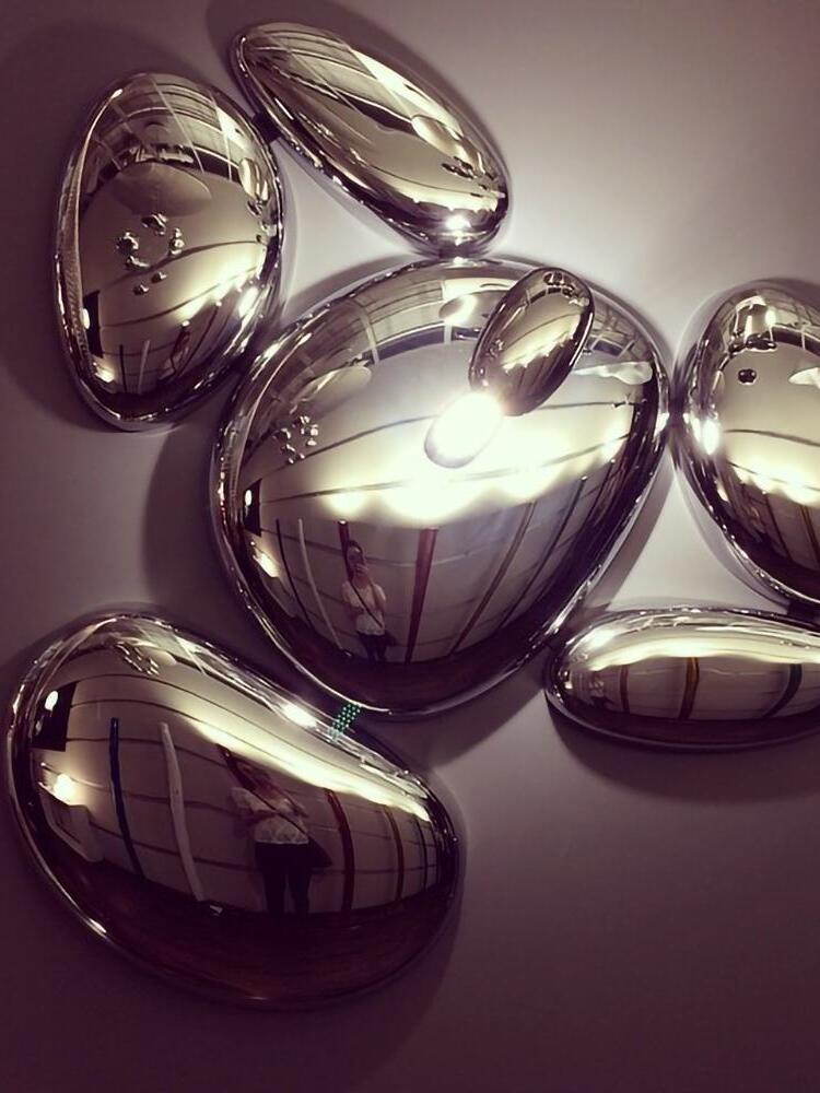 Close mirror-finish rounded pebble forms reflecting light and surrounding room