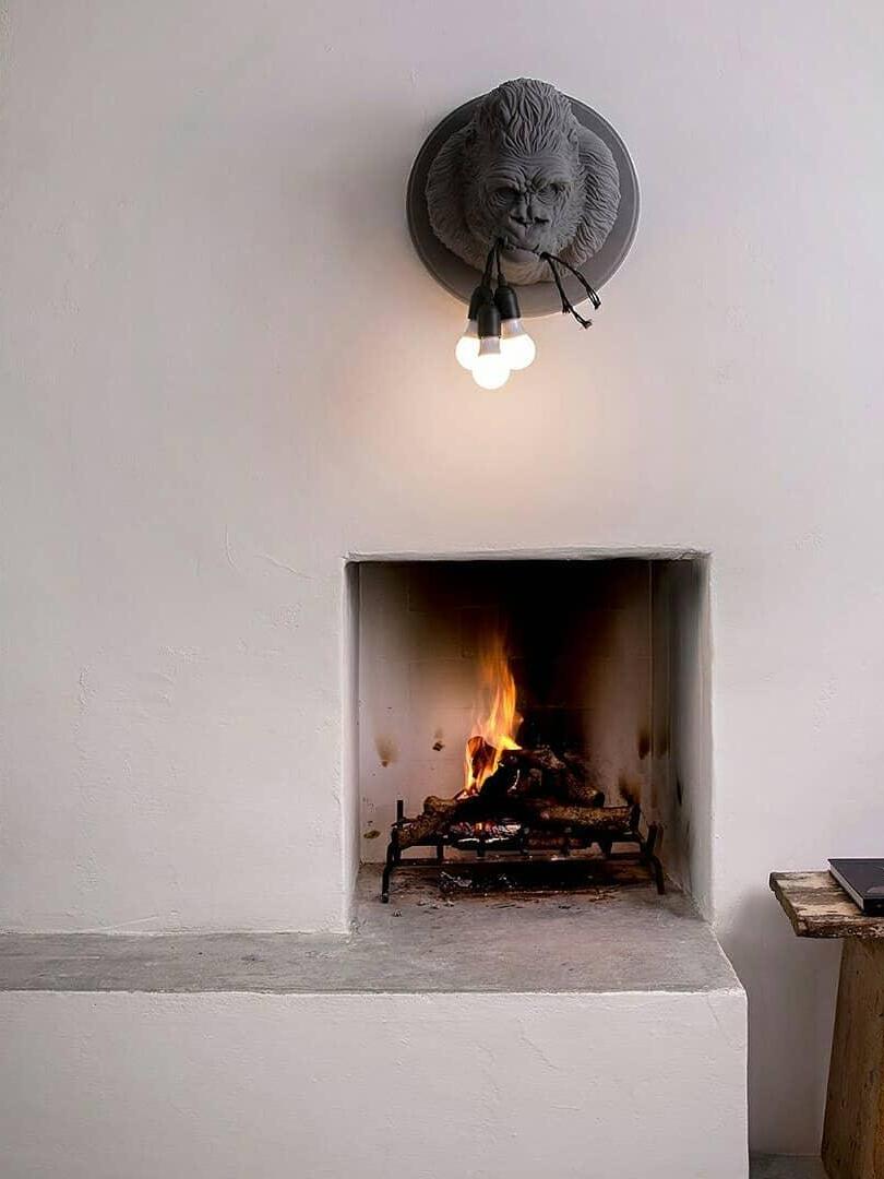 Dark gorilla wall light above recessed fireplace in pale room