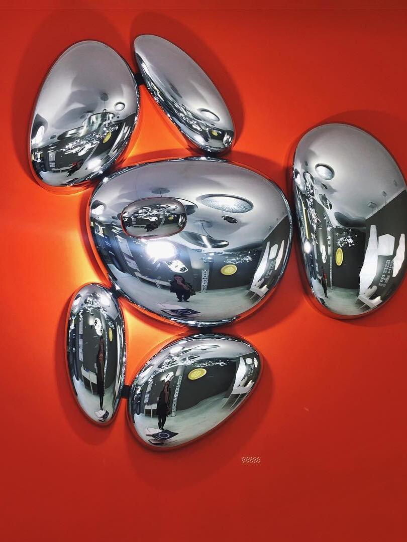 Five reflective pebble forms against red background without visible hanging unit