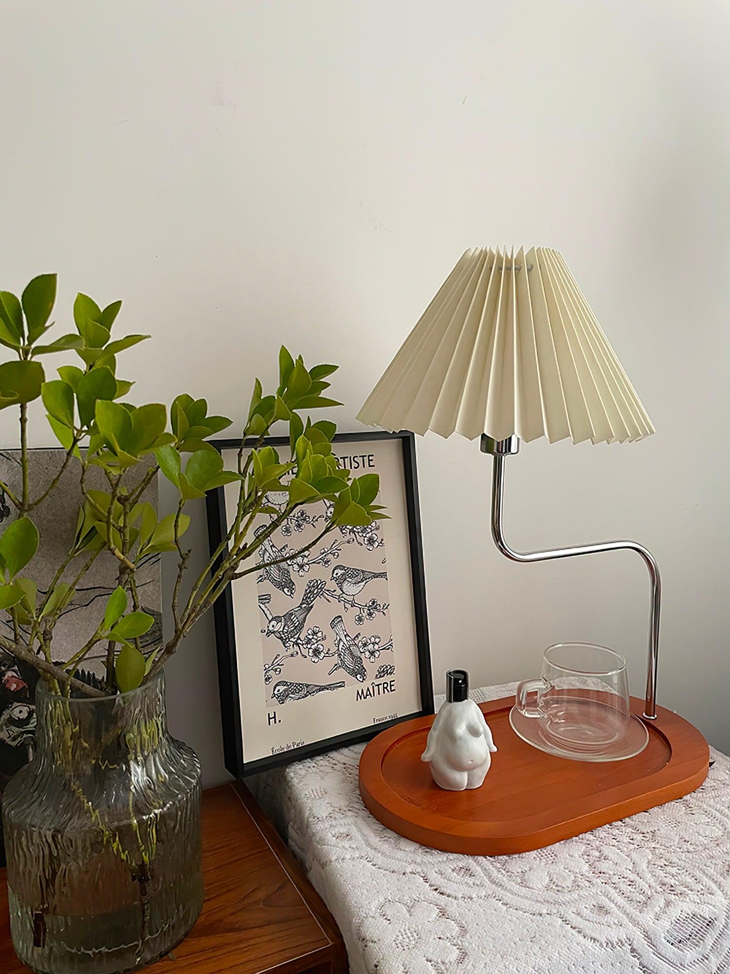 Unlit pleated-shade lamp beside green plant