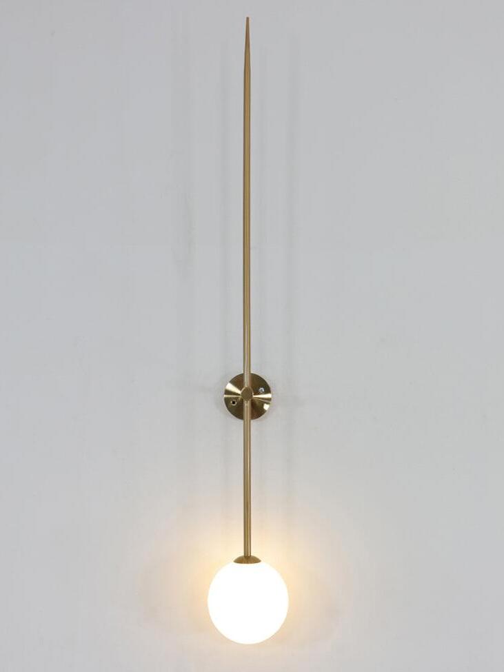 Frontal lit gold-tone rod wall light with a glowing white globe against a pale wall