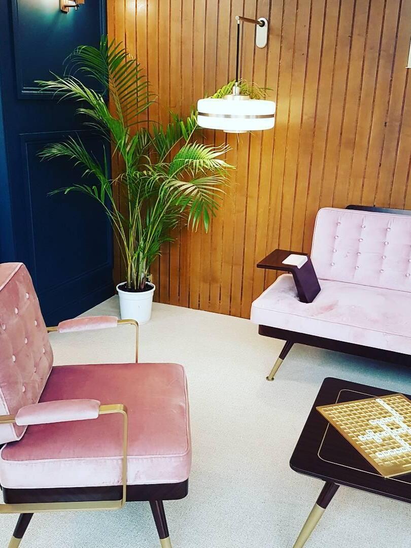 Lit white banded wall shade above pink seating on wood-panelled wall