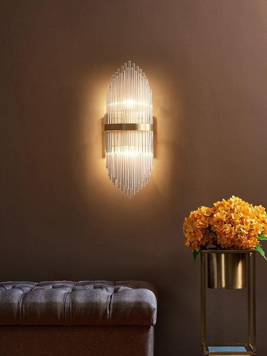 Warm brass and crystal sconce above dark sofa and flowers