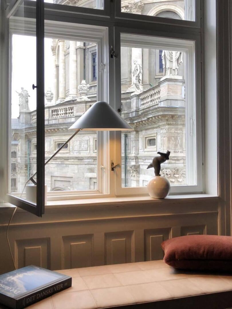 Angled-shade lamp on a wood worktop beside an open window and small vase