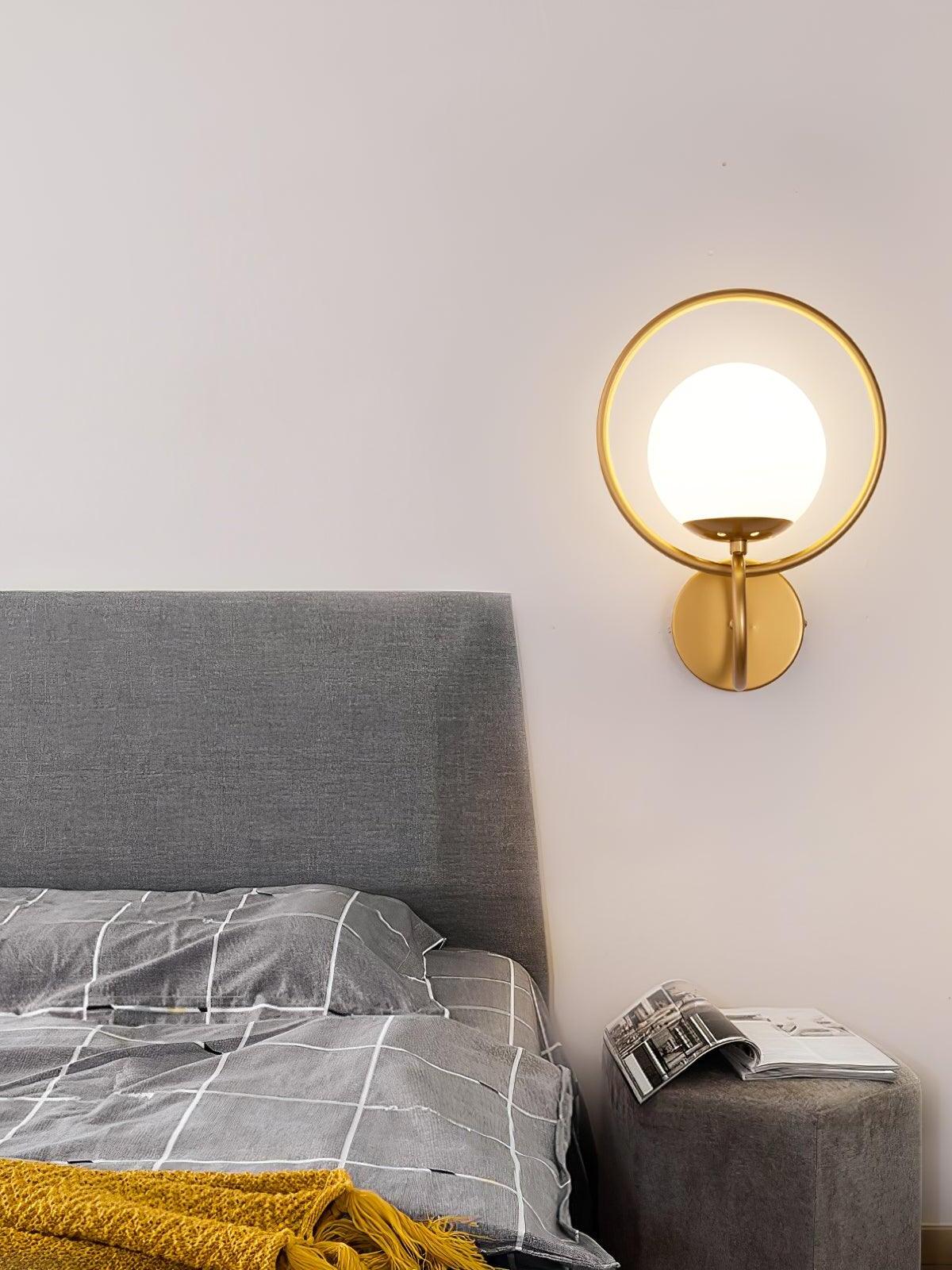 Gold ring globe wall light above grey bedhead