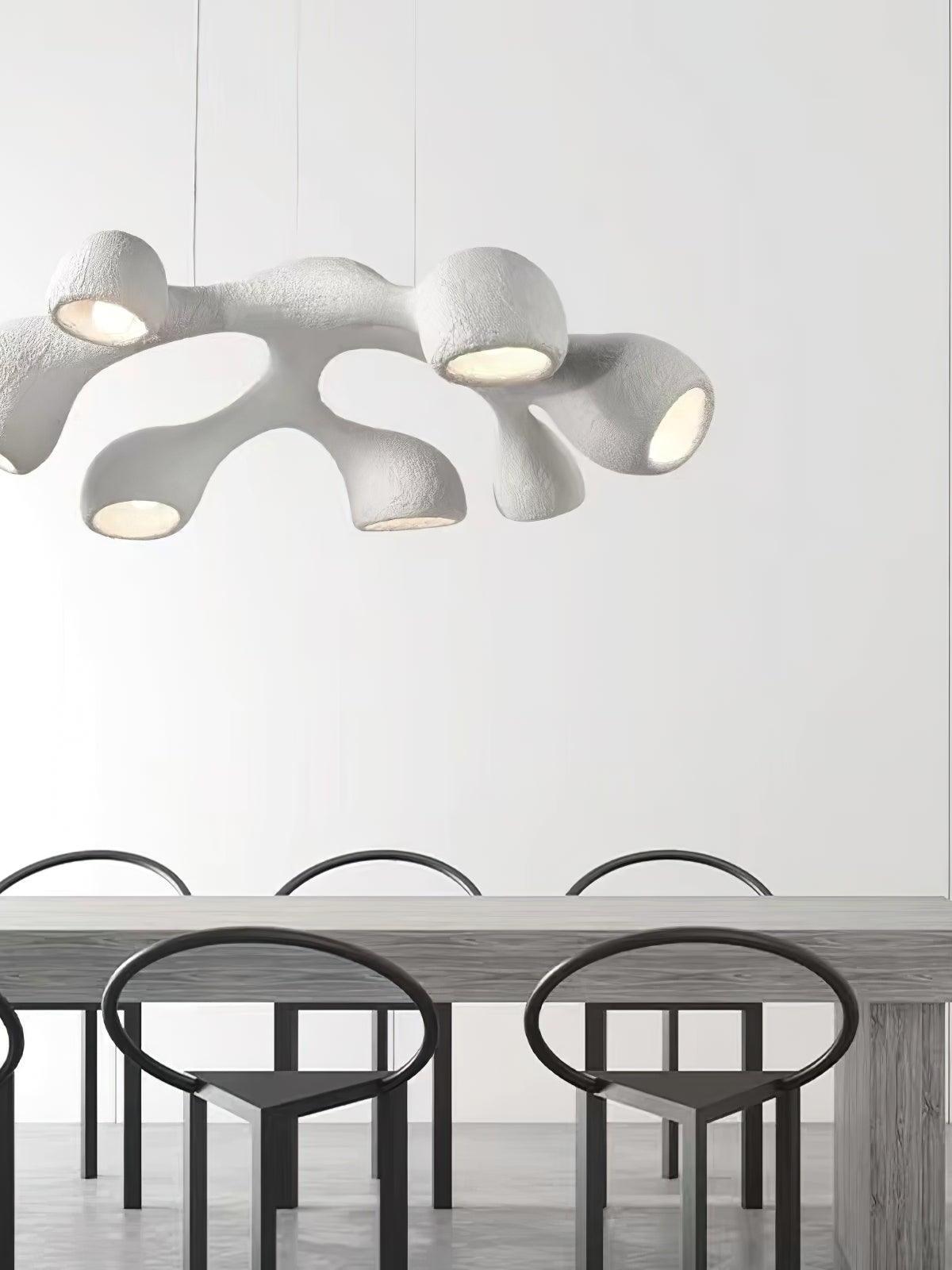 White looped branching pendant above a long wooden dining table with black oval-back chairs