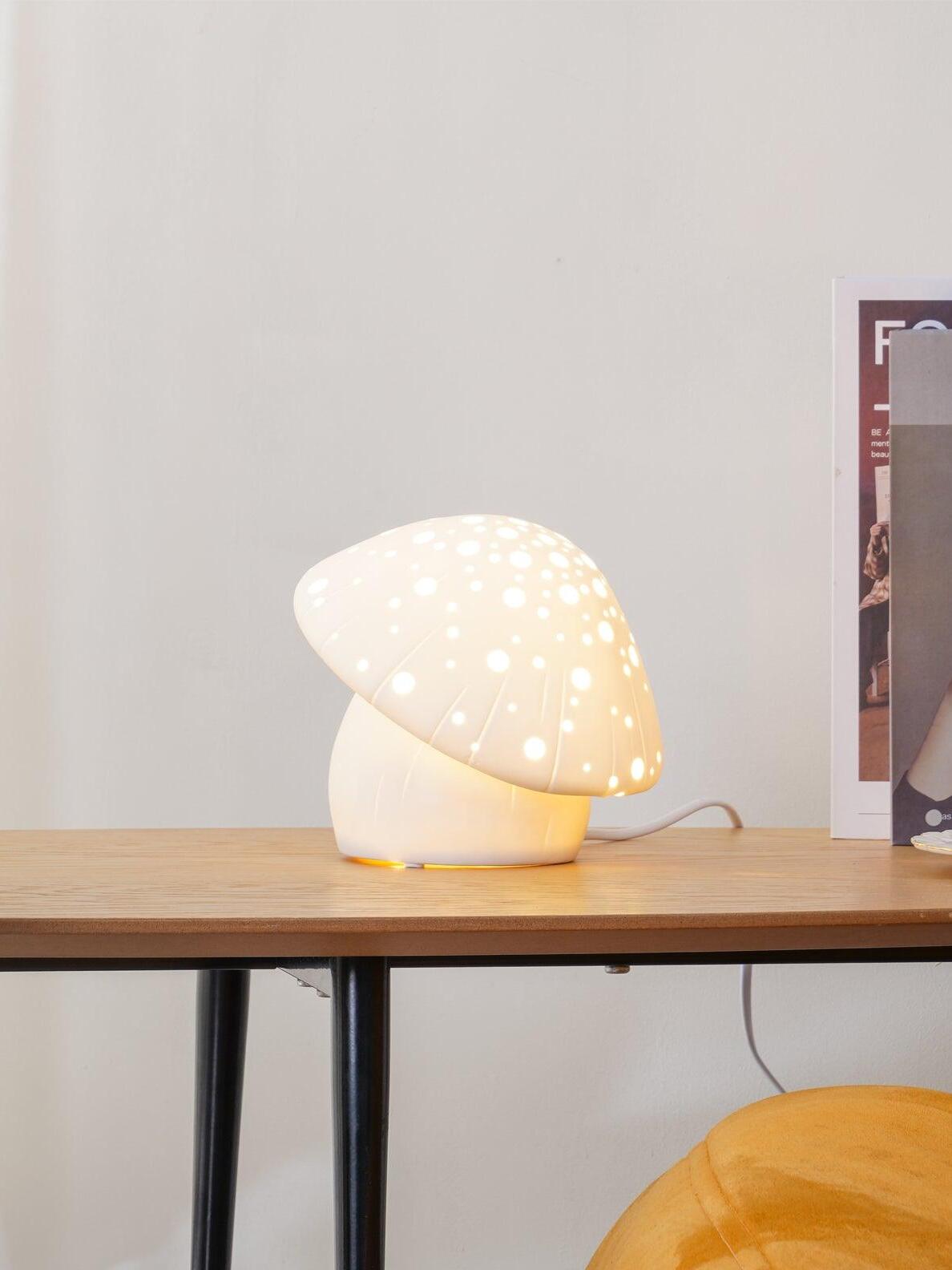 Lit Fungo lamp beside books on a wooden desk near an orange seat