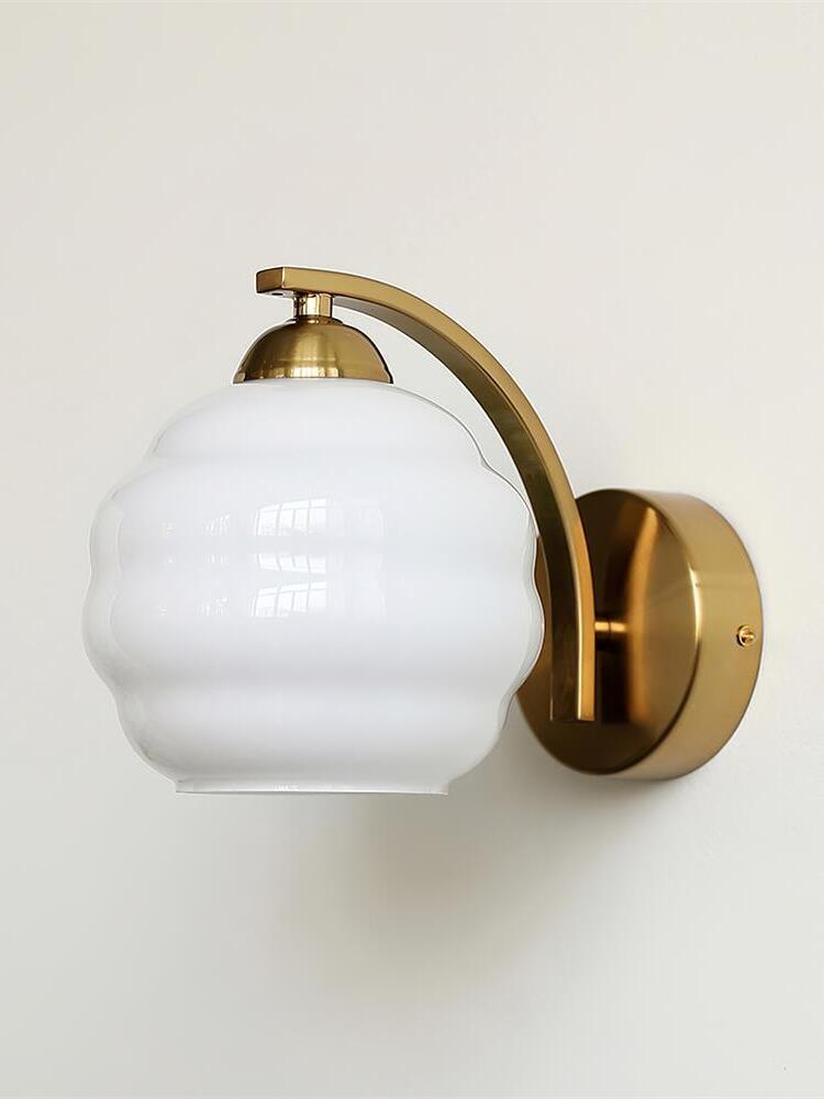 White contoured glass shade supported by a gold-colored arched arm, domed cap and circular wall plate