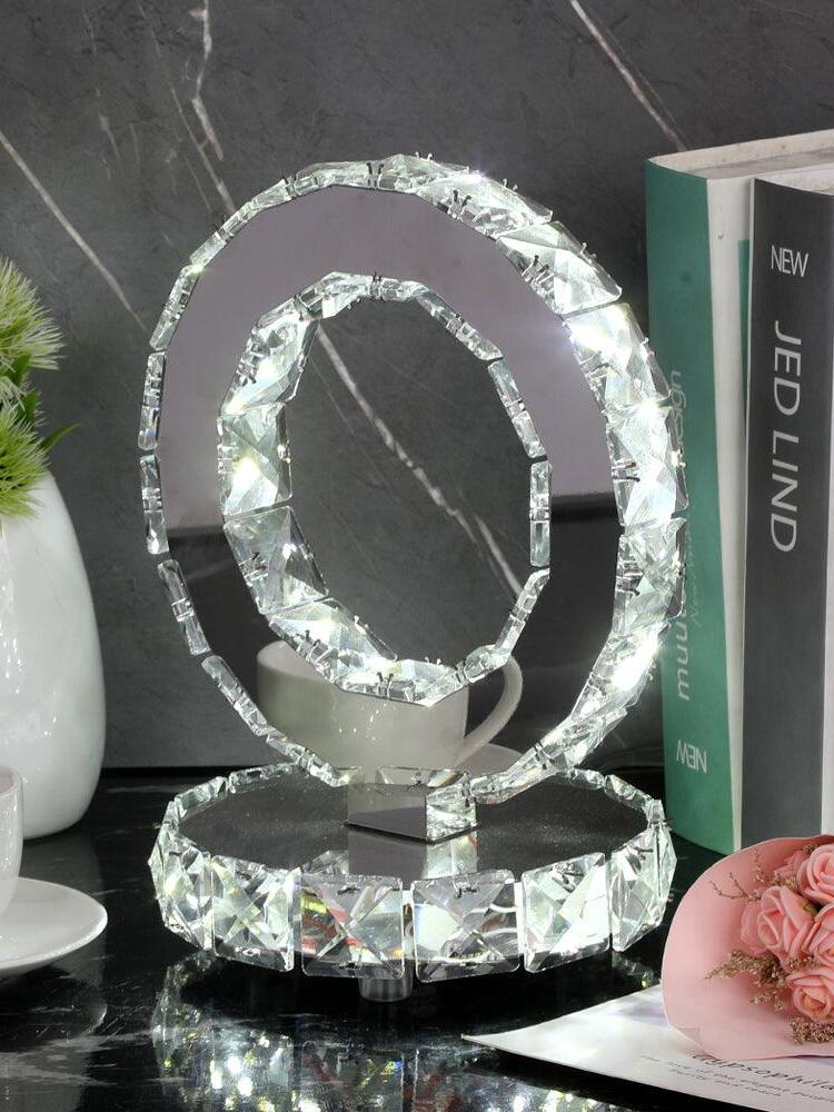 Crystal Rings lamp beside books and flowers against a dark veined wall