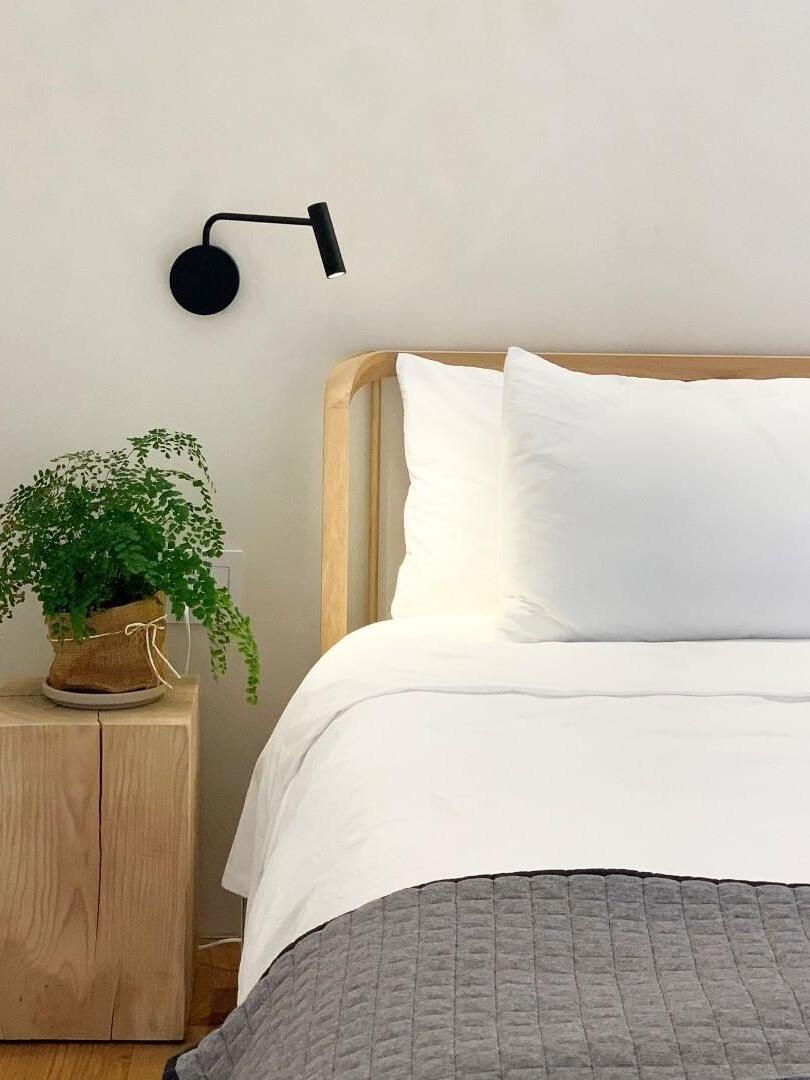 Black reading sconce next to white bedding