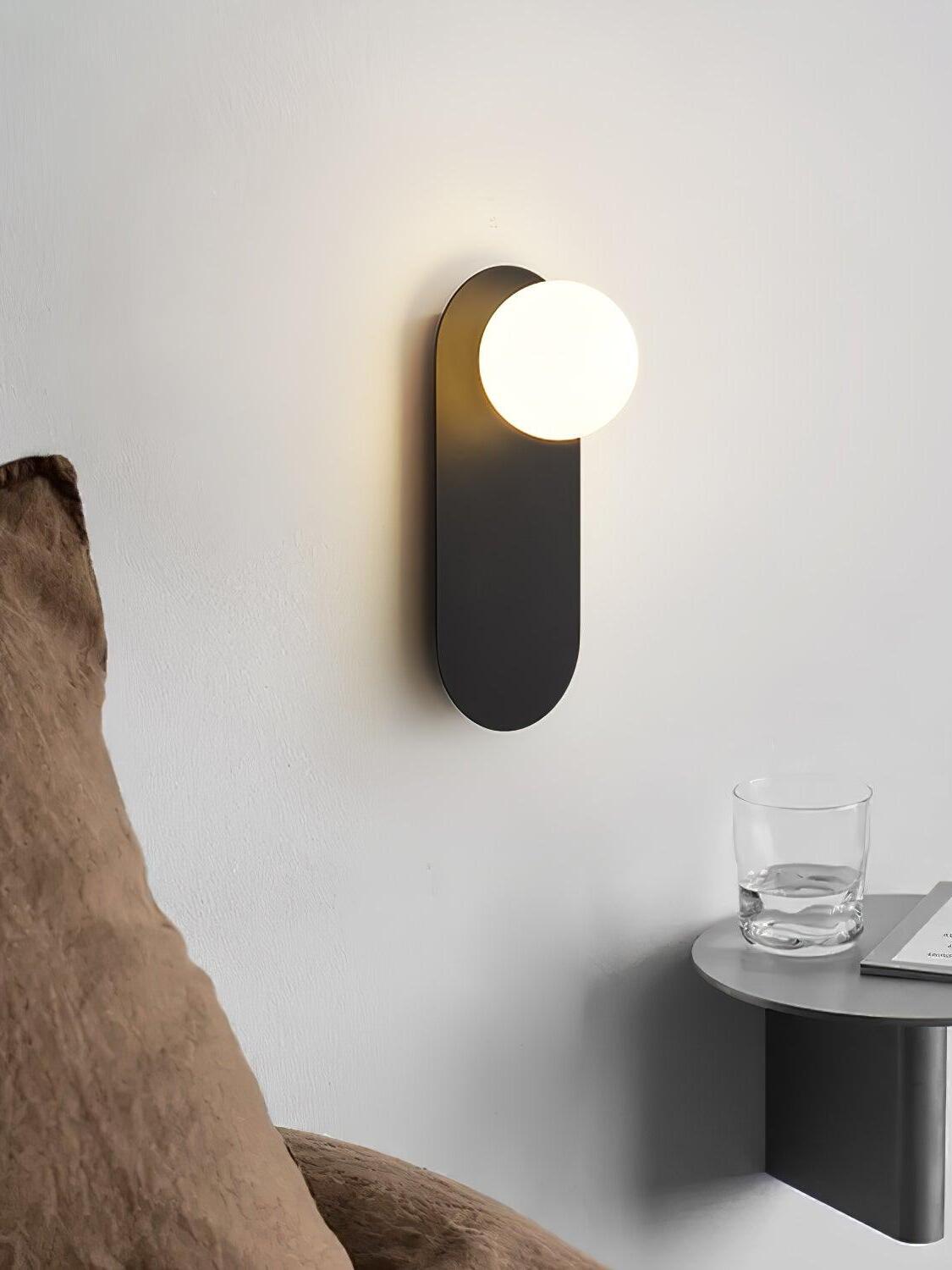 Black globe wall light beside a small shelf