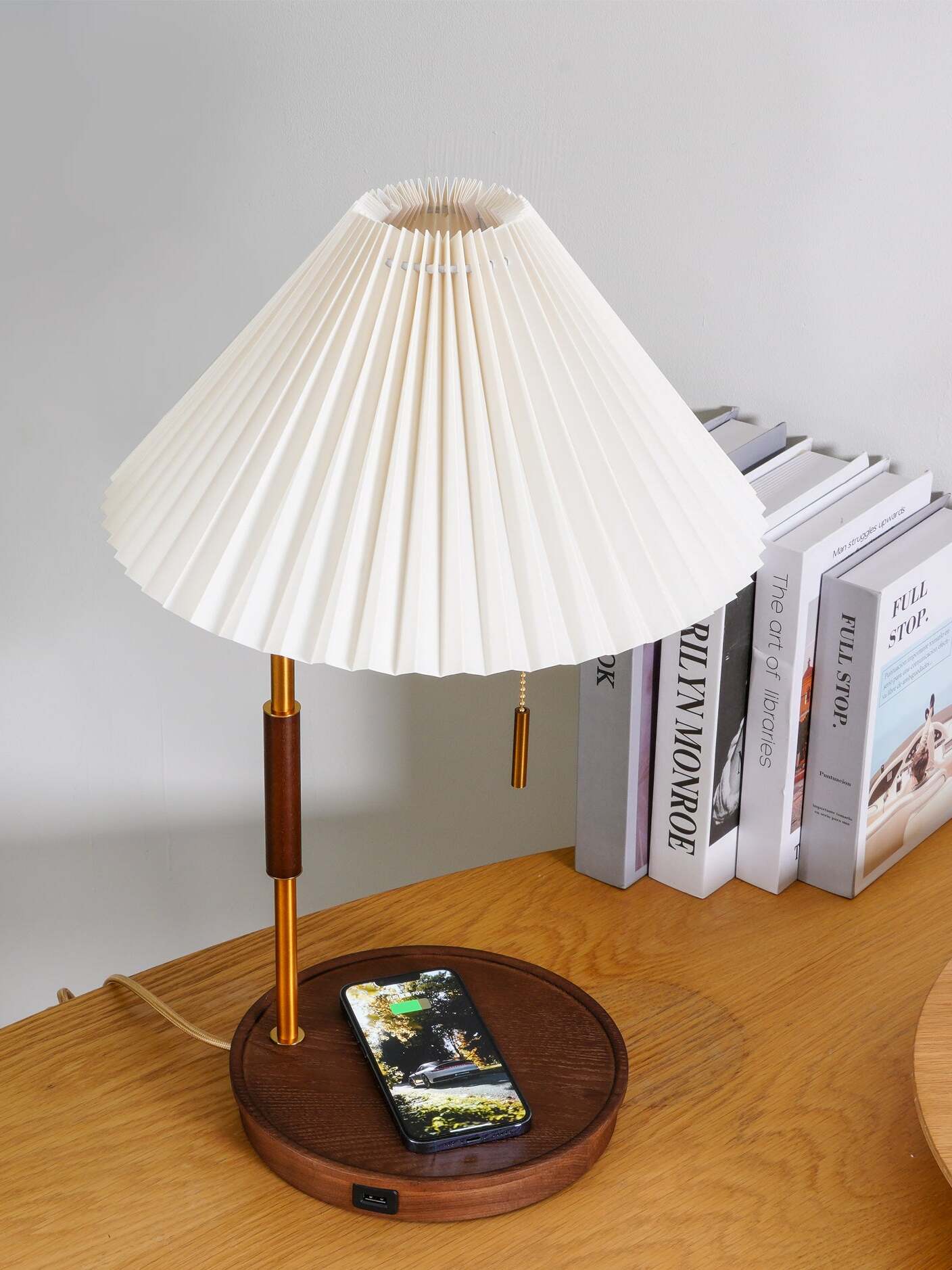 Angled view of the white pleated shade above a dark circular base with a phone resting on it