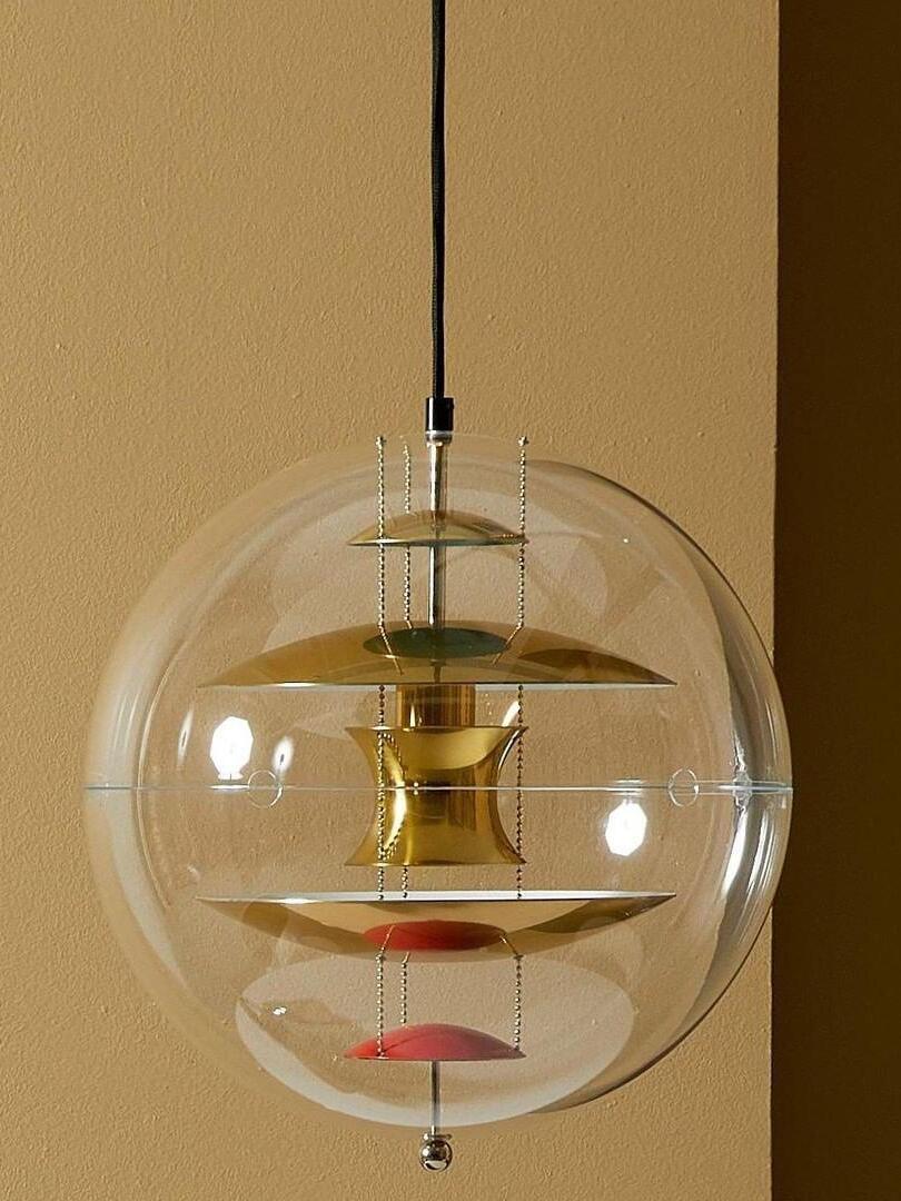 Close-up of gold-tone reflectors and bead chains inside a clear globe against a warm textured wall