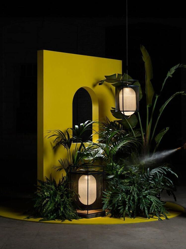 Hanging and floor-standing black lanterns among plants